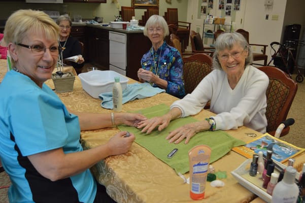 Residents enjoying a manicure activity with staff assistance