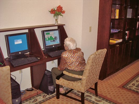 An elderly woman using a computer in a common area