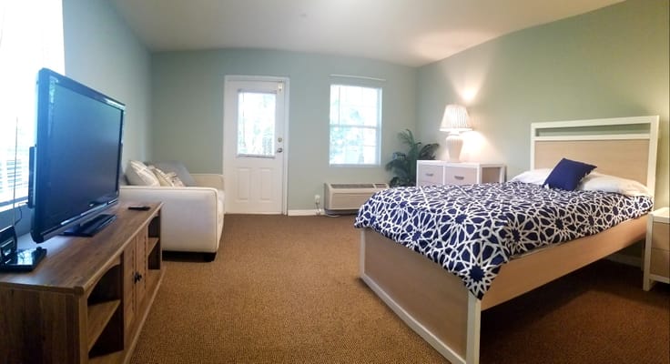 Cozy resident room with bed, seating area, and TV