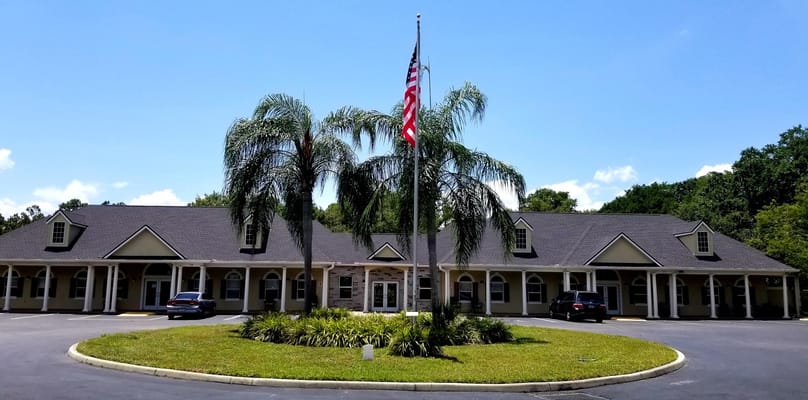 Exterior view of the facility with palm trees and flag