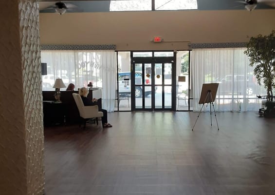 Interior lobby with residents seated and an easel