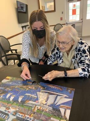 Resident and staff member completing a puzzle together