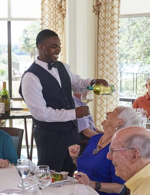 Server pouring wine for a resident at dinner