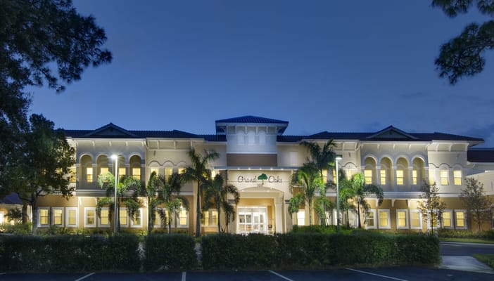 Exterior view of Grand Oaks at dusk with illuminated entrance