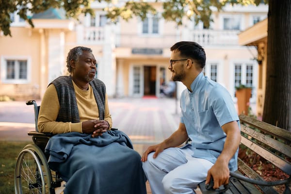 A resident and staff member chatting outside