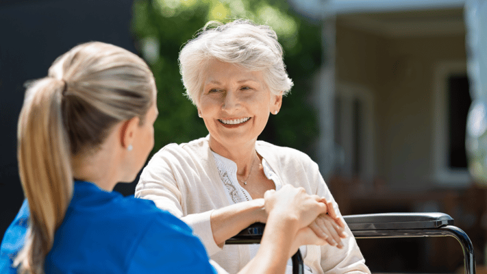Care staff interacting with a smiling resident outdoors