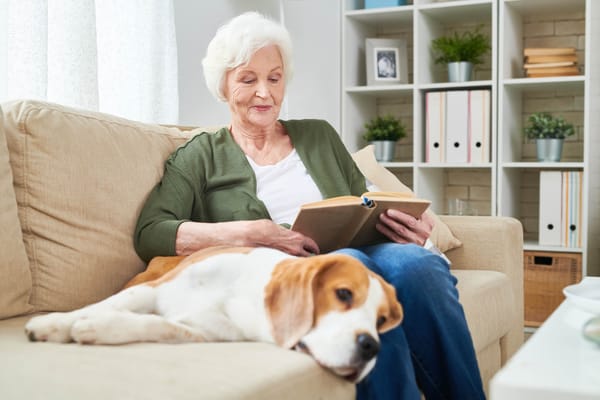Senior reading on a couch with a dog