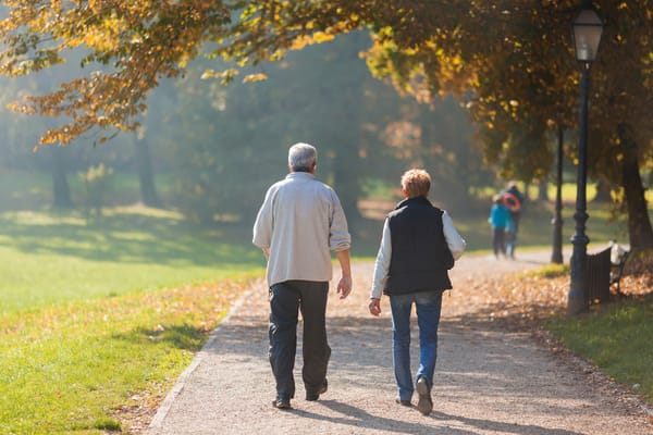 Two seniors walking together in a sunlit park