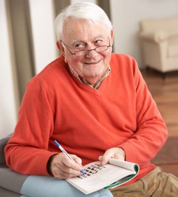 A senior man writing in a notebook in a cozy interior setting