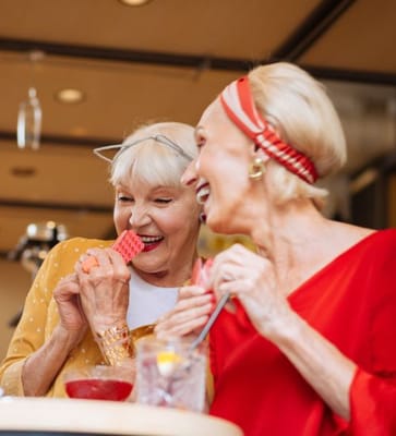 Two smiling women enjoying a fun activity indoors