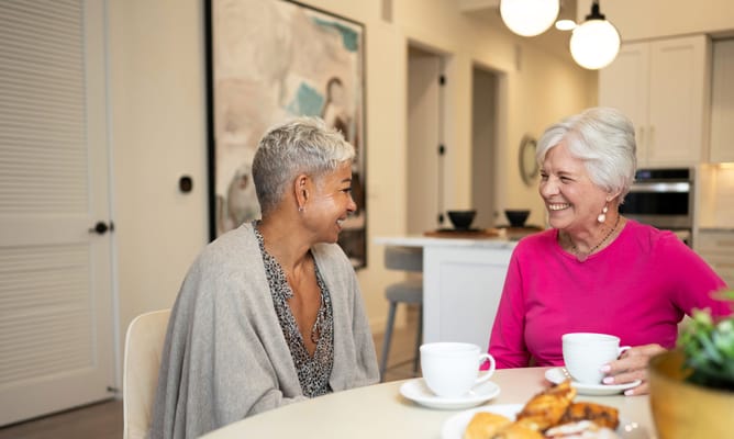 Two residents enjoying coffee and pastries in a common area