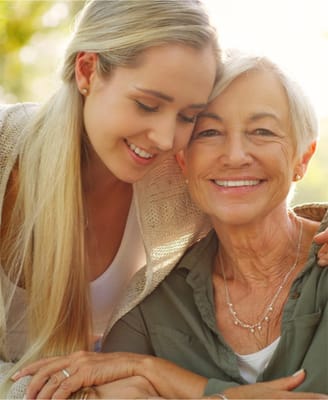A woman smiling with her grandmother outdoors