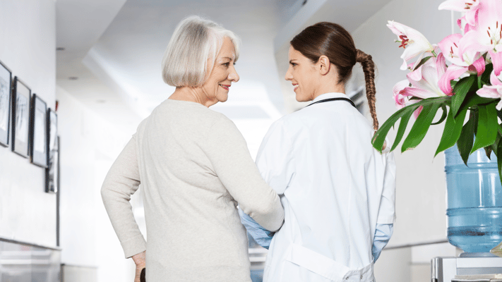 A resident smiling with a caregiver in a hallway