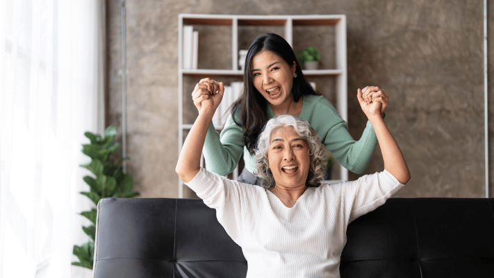 Two women celebrating joyfully in a living space