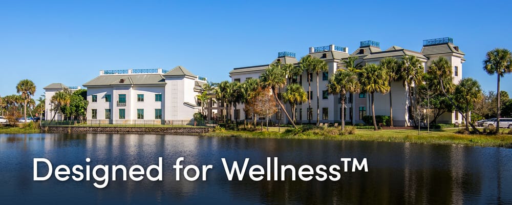 Exterior view of Luxe Senior Living at Wellington by a lake