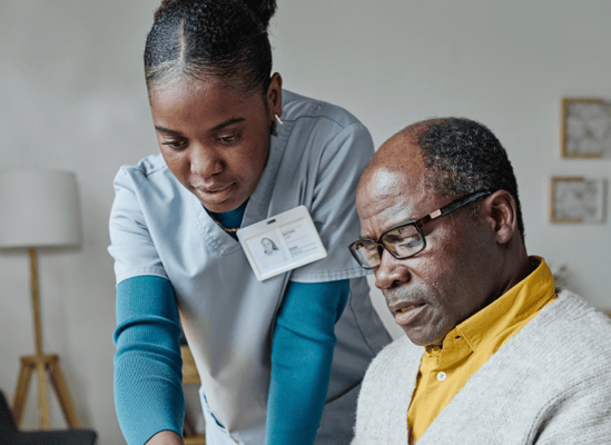 Staff assisting a resident with a device in a cozy interior