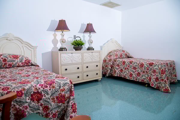 A shared resident room with floral bedding and lamps