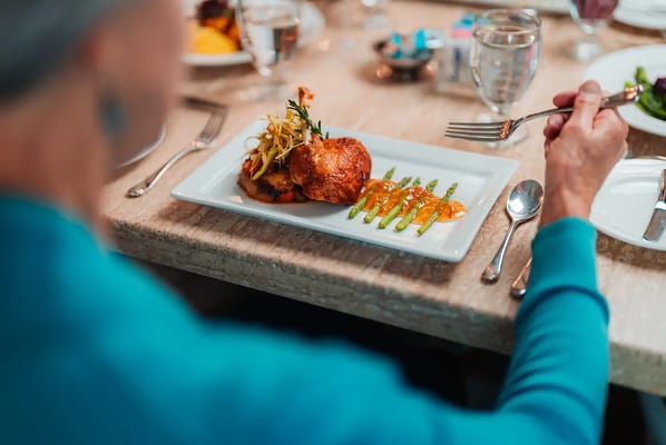 A resident enjoying a plated meal in the dining room