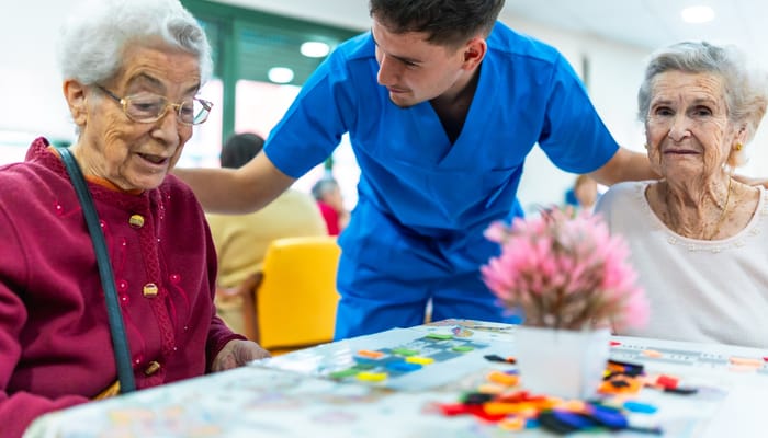 A caregiver interacting with two residents at a table