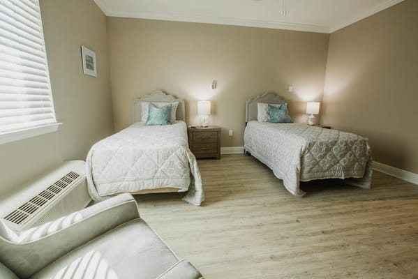 Bright, clean resident room with two beds and seating area