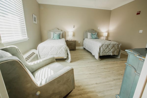 Brightly lit resident room with twin beds and sitting area