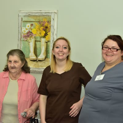 Staff members posing with a resident in an activity room