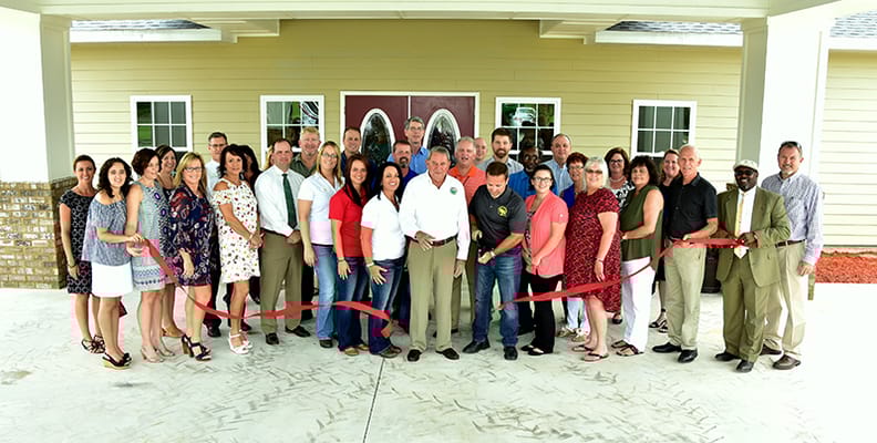 Group photo during a ribbon-cutting ceremony outside the facility
