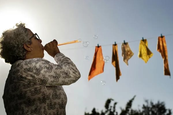 Resident enjoying outdoor bubbles with colorful cloths hanging