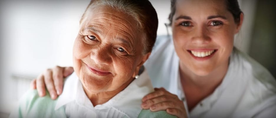 Caregiver with a resident smiling at the camera