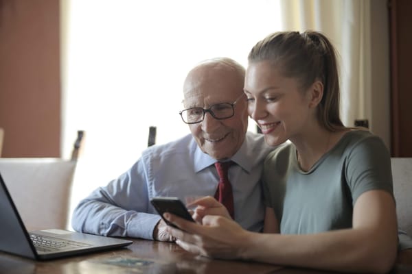 Smiling senior man and young woman looking at a phone together