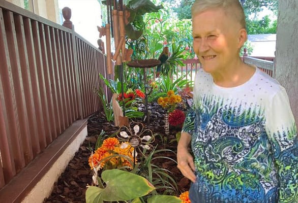 A resident smiling in a colorful flower garden