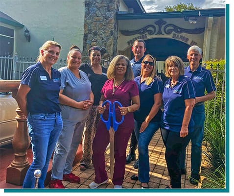 Staff posing in front of the facility entrance with large scissors