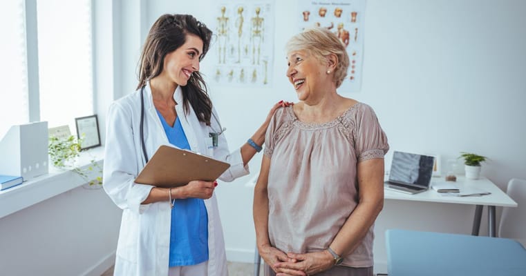 A nurse discussing with an elderly woman in a medical office