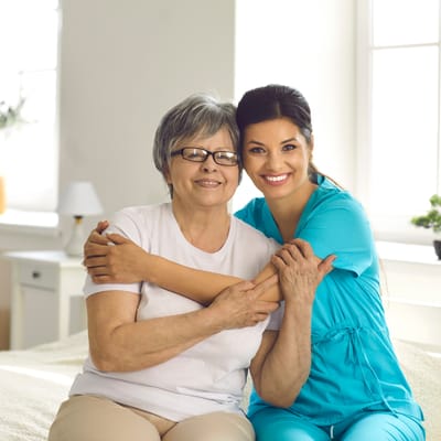 Resident and caregiver smiling together in a bright room