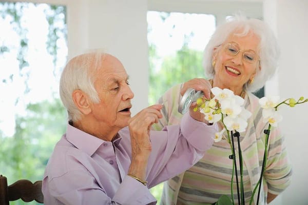 Two residents enjoying floral arrangements in a bright common area