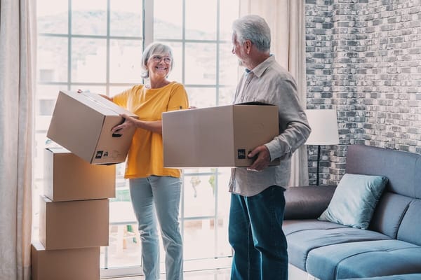 Two seniors smiling while unpacking boxes in an apartment