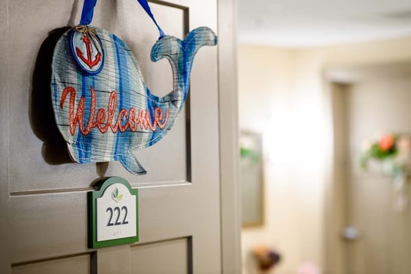A warmly decorated door with a whale welcome sign
