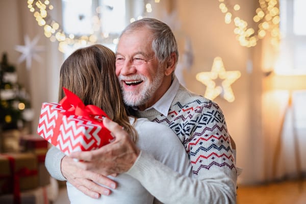 A resident hugging a visitor with a gift during a celebration
