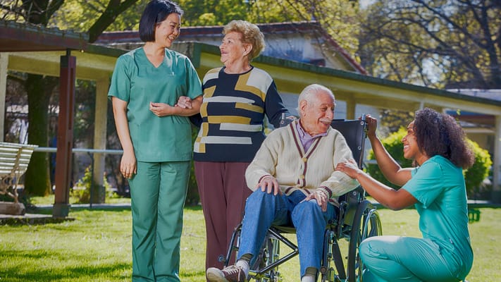 Care staff assisting elderly residents in a garden