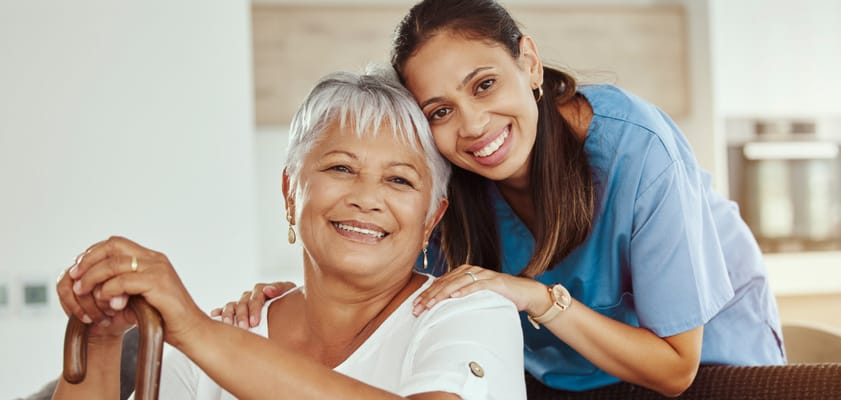 A caregiver and resident smiling in an interior space