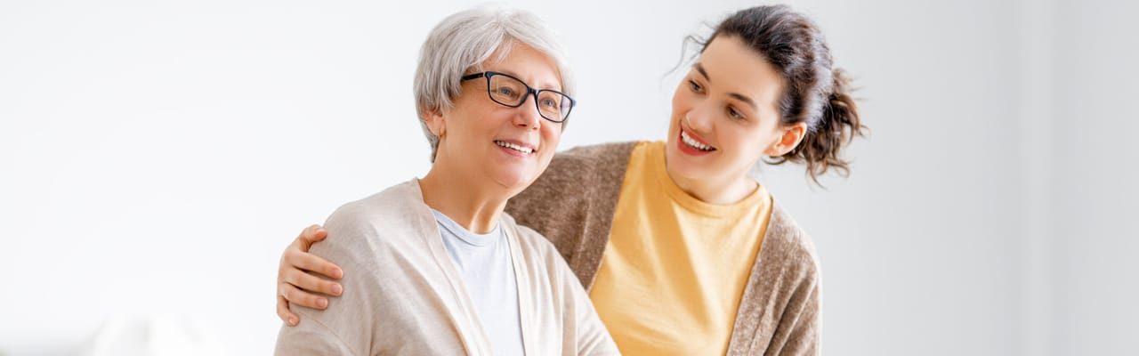 Senior resident smiling with staff in a bright room