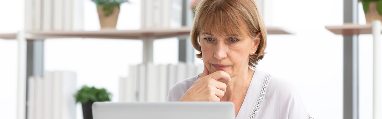 Senior woman thoughtfully using a laptop in a bright room