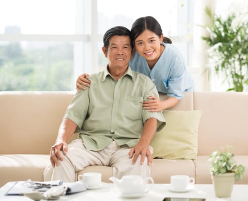 A caregiver and resident smiling together on a couch