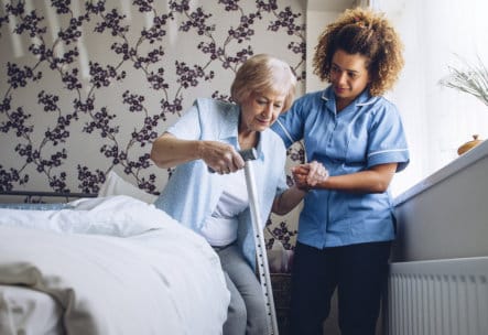 A caregiver assisting a senior resident in a bedroom