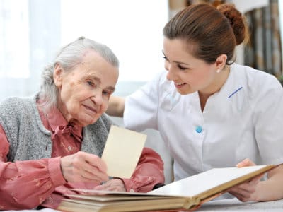 A caregiver assisting an elderly resident with a photo book