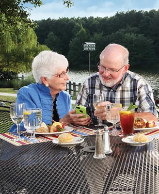 Two seniors enjoying a meal by the lake
