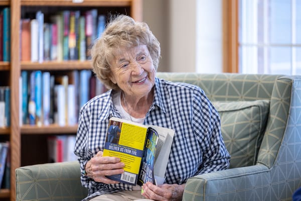 Senior resident smiling while reading a book