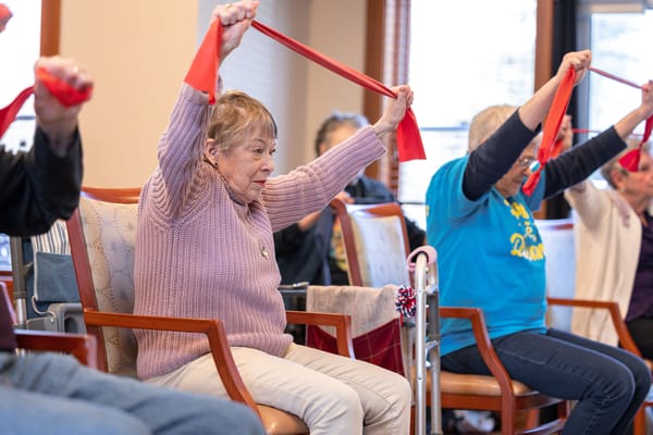 Residents participating in a seated exercise class indoors