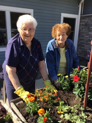 Two residents happily gardening outdoors