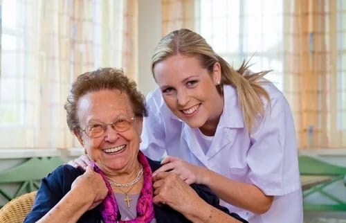 A caregiver and a smiling resident in a common area